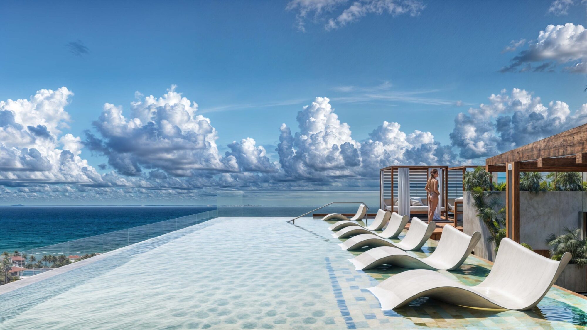 Alberca infinita en la terraza de Macondo Corazón con camastros sumergidos, vista panorámica al mar Caribe, pérgolas de madera, palmeras decorativas y cielo azul con nubes sobre Playa del Carmen. Un espacio exclusivo dentro de los departamentos en venta en Playa del Carmen que combina lujo y tranquilidad.