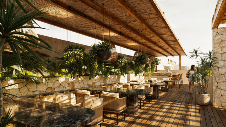 Rooftop bar de Macondo Corazón en Playa del Carmen con mesas de mármol oscuro, sillas de fibras naturales, techo de madera con lámparas colgantes, plantas tropicales suspendidas y un ambiente cálido con luz natural. Un espacio distintivo dentro de los departamentos en venta en Playa del Carmen, ideal para disfrutar del entorno caribeño.
