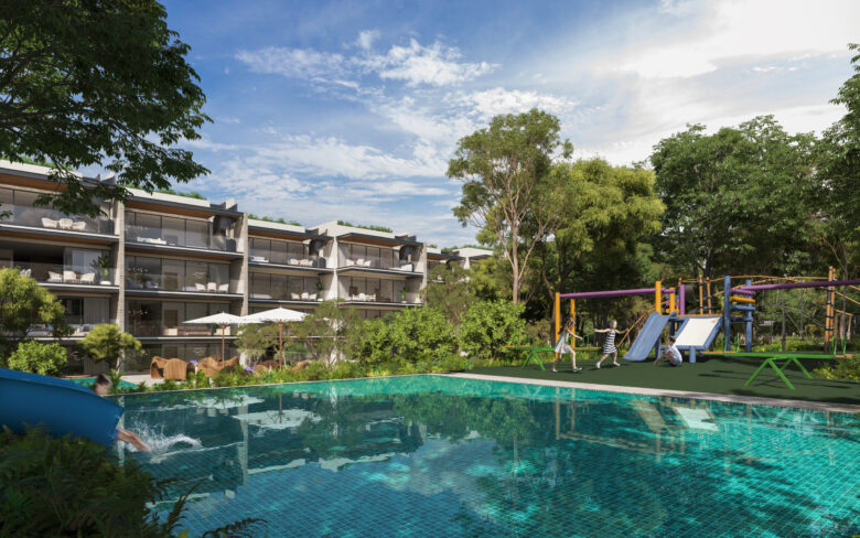 Área de juegos infantiles en Macondo Playacar con resbaladilla, columpios y estructuras de colores, rodeada de jardines tropicales; junto a una alberca infantil con tobogán y vista hacia los edificios residenciales con terrazas amplias. Espacios pensados para familias que buscan departamentos en venta en Playa del Carmen con amenidades que inspiran bienestar.