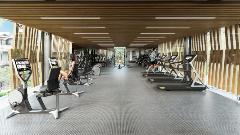 Gimnasio en Macondo Playacar con modernos equipos de entrenamiento, iluminación natural, piso antiderrapante, diseño contemporáneo con acabados de madera y ventanales amplios que ofrecen vista hacia la vegetación exterior. Espacio exclusivo para residentes de los departamentos en venta en Playa del Carmen que buscan equilibrio y vitalidad.