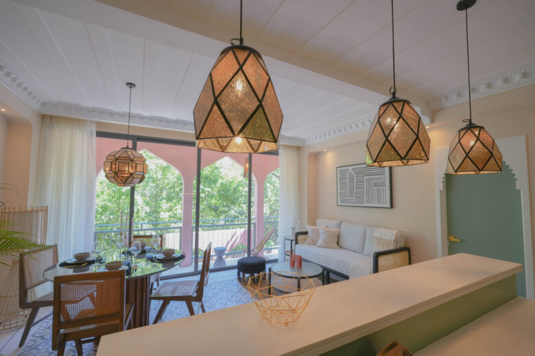 Vista al interior de una unidad en Pink Riad Tulum, donde el comedor y la sala se integran con la terraza exterior. Lámparas geométricas, tonos suaves y detalles artesanales evocan la esencia de un riad marroquí rodeado de naturaleza. Espacio distintivo dentro de los departamentos en venta en Tulum.